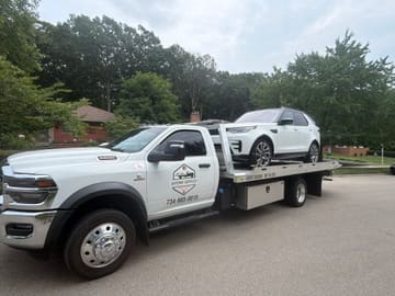 Safeway Services tow truck hauling a white Land Rover through a residential neighborhood