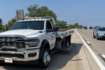 Safeway Services flatbed tow truck stopped on a highway shoulder beside passing traffic