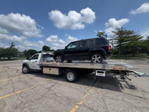 Black Jeep loaded on a Safeway Services tow truck in a parking lot