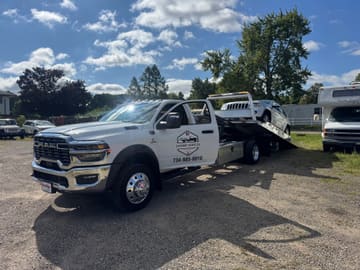 White Jeep Grand Cherokee being loaded up the tilted deck of a Safeway Services flatbed