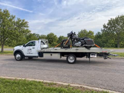 Harley-Davidson motorcycle strapped upright on a Safeway Services flatbed, parked roadside